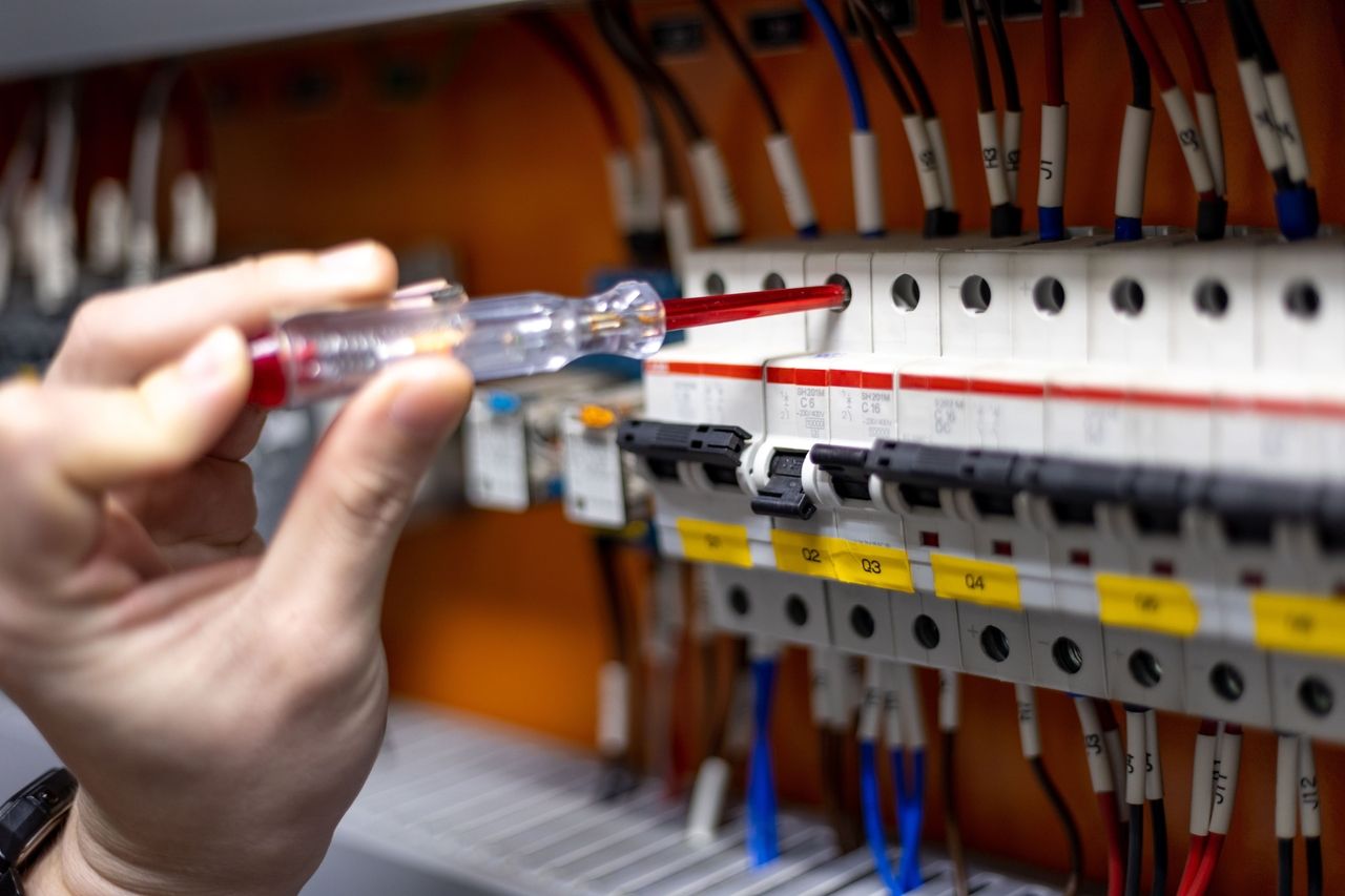 Nahaufnahme einer Hand bei der Elektroinstallation mit einem Schraubenschlüssel